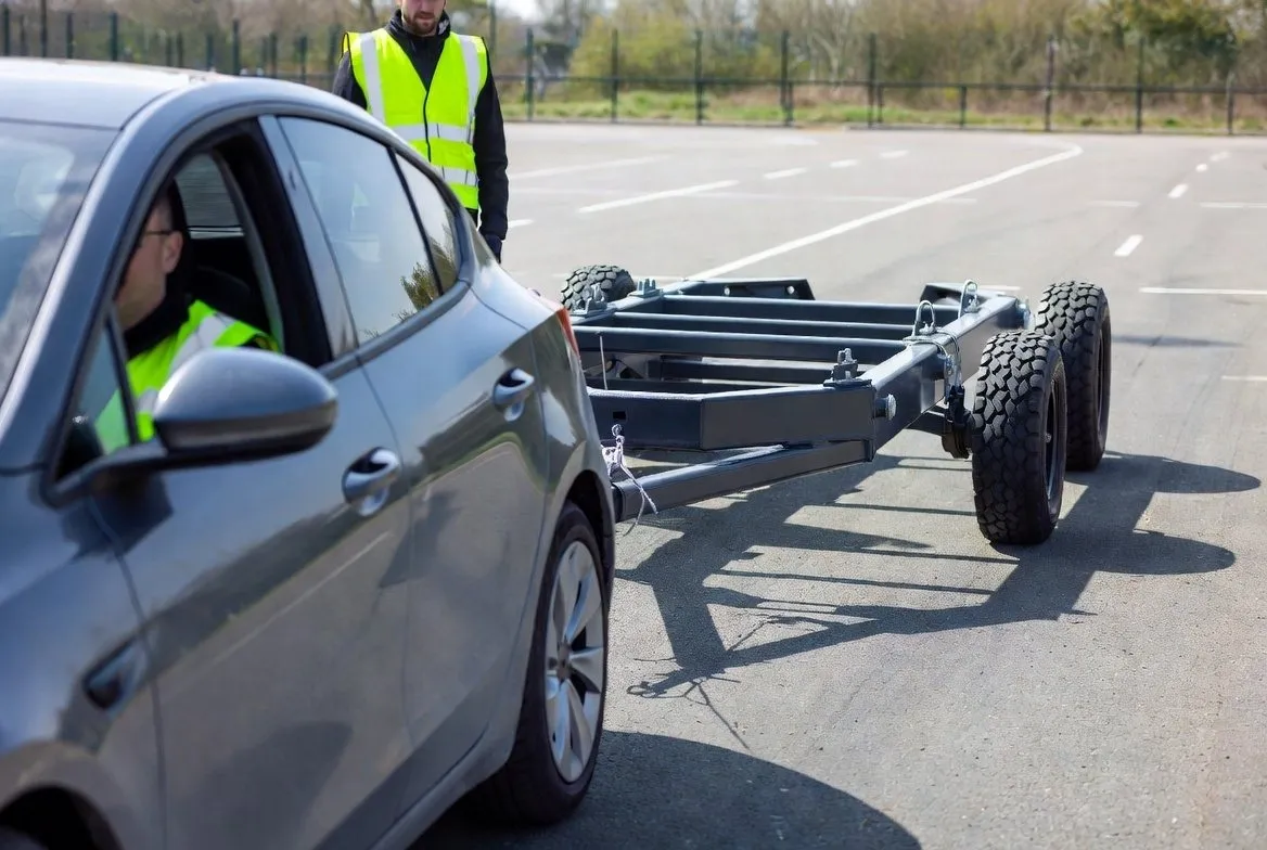 Cursist rijdt een auto met aanhanger achteruit, instructeur kijkt mee