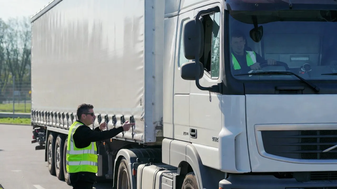Instructeur wijst iets aan bij een vrachtwagen met oplegger