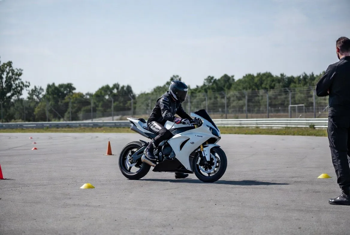 Motorrijder op een oefenterrein met de instructeur op de achtergrond