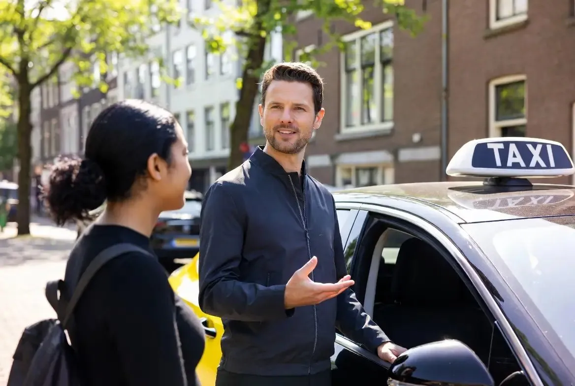 Taxichauffeur in gesprek met een klant naast de auto