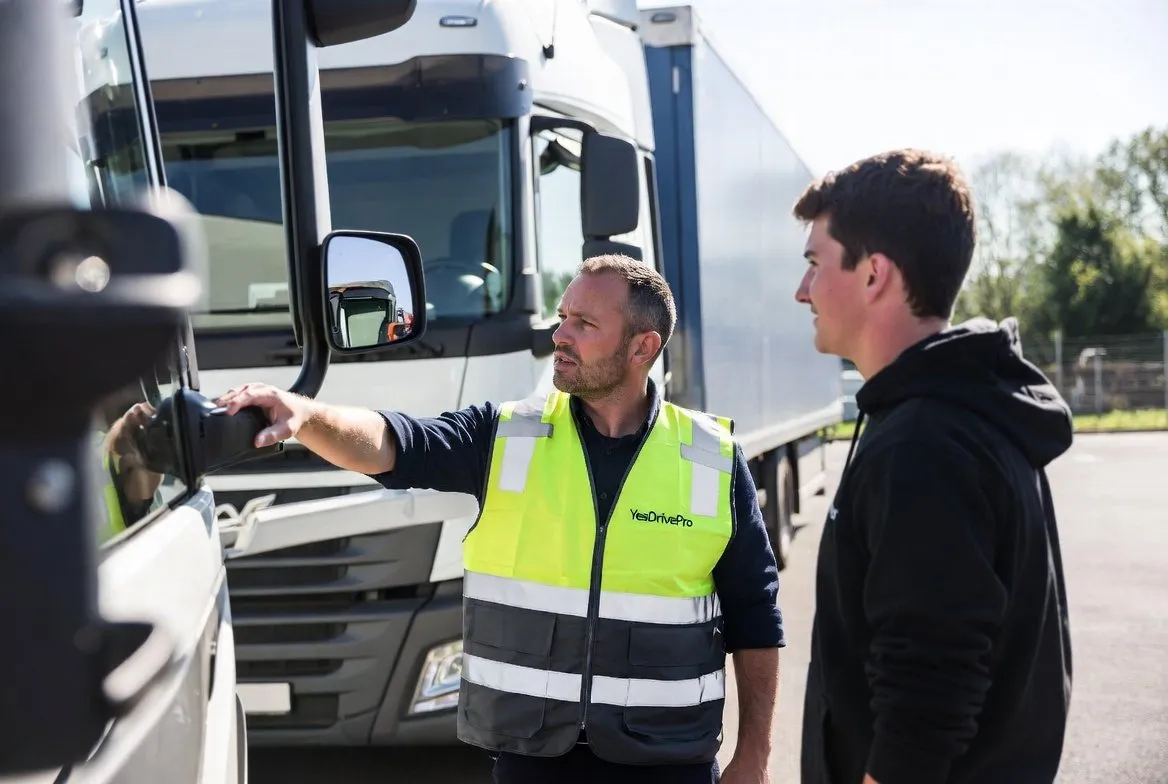 Instructeur legt een cursist iets uit bij de cabine van een vrachtwagen